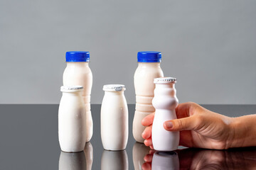 Yoghurts containing probiotics, bifidobacteria and vitamins. Hand with white bottles of milk drink as probiotic food concept. Bifidobacteria and Probiotics for digestive immunity.