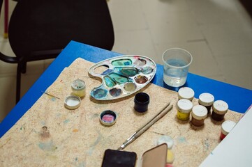 Drawing lesson. Palette and jars of gouache on table