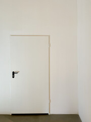 Weiße Türe mit schwarzem Griff in weißer Wand
