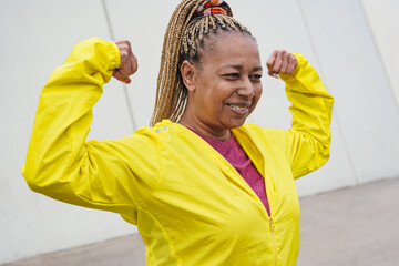 Senior african woman showing biceps muscle during sport workout in the city