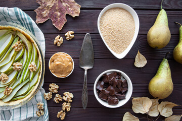 Assortment of fruit autumn pie or tart ingredients on brown table, top view. Sugar, caramel, pear tart and chocolate. 