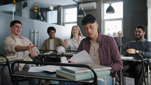 Students sitting in classroom laughing at classmate young frustrated worried guy suffering from ridicule bullying abuse feels like loser upset distressed oppressed student feeling loneliness offended