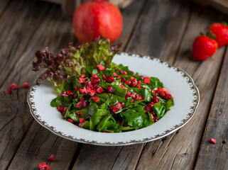 rocca salad with strawberry and pomegranate sauce served in a dish isolated on wooden background side view