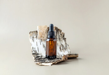 bottle with a pipette and birch bark on a gray background