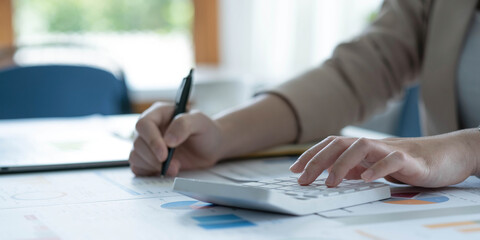 Businesswoman accountant working audit and calculating expense financial data on graph documents, doing finance in workplace.