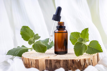 bottle with a pipette with cosmetic essential oil and mint sprigs on a wooden board