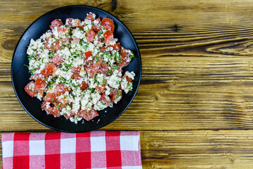 Salad with tomatoes, cottage cheese, dill and olive oil on a wooden table. Top view
