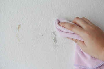 woman cleaning and remove sticky rough glue and tape remain on the old concrete wall.
