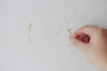 woman cleaning and remove sticky rough glue and tape remain on the old concrete wall.