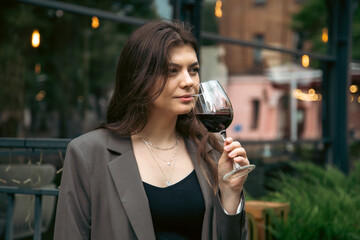 A young woman with a glass of wine outside near a restaurant.