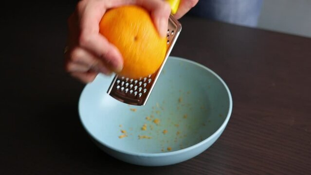 woman zesting orange at home close up