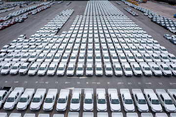 Aerial front view new cars lined up parked in a row in warehouse at the commercial dock for exporting to distributors and dealers international business logistics and transportation by container ship 