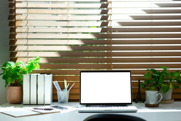 Front view of creative hipster desktop with laptop, stationery and photo frame with wall holder.