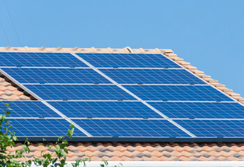太陽光パネルが設置された住宅の屋根と快晴の青空。