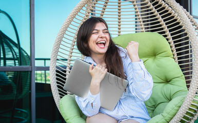 Satisfied young woman after a working day with a laptop in a hammock.