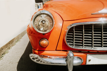Detail of retro automobile brand, headlight close-up view. Orange roadster. Symbol of vintage car maker and producer 