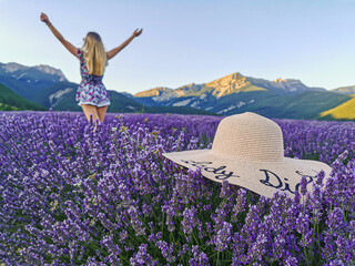 A hat in a lavender field with a young woman with her arms raised against the backdrop of the...