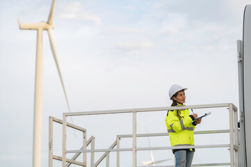 Naklejka premium women engineer working and holding the report at wind turbine farm Power Generator Station on mountain,Thailand people