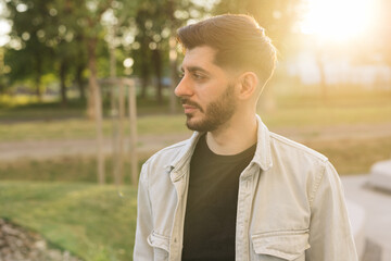 Caucasian european man looking stright outdoors. Stand outdoor relax. Gorgeous face of young bearded mixed-race elegant man with brown eyes. Male portraits.