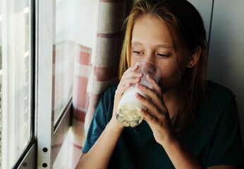 Portrait of a teenager girl at home with glass of milk - 517535289