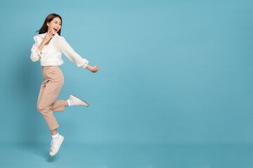 Young beautiful asian woman with smart casual cloth jumping and smiling with excitement looking at...