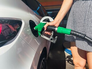 A woman filling up her car at a gas station.