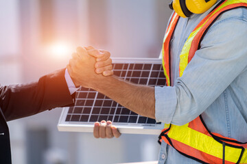 Close up businessman and engineers shaking hands after discussing install solar panels on houses under construction,Renewable energy for residential.