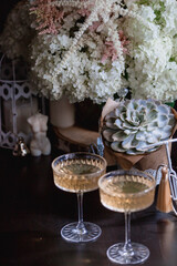 A bouquet of white hydrangeas and pink astilba, succulent, candles and a fashionable glass for dessert and champagne with wine inside. Cozy interior. The concept of a party, wedding and holiday.