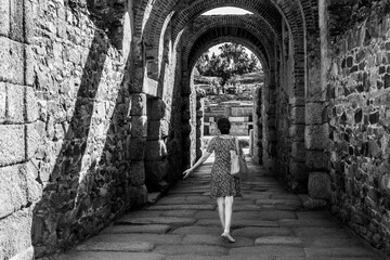 Woman advancing through a stone corridor towards the Roman Amphitheater in Mérida, as if she were an actress or dancer who goes on stage