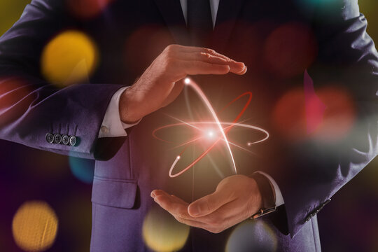 Man holding virtual model of atom on color background, closeup