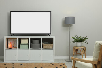 Modern TV on cabinet near light wall indoors. Interior design