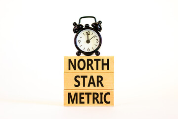 North star metric symbol. Concept words North star metric on wooden blocks on a beautiful white table white background. Black alarm clock. Business, finacial and north star metric concept. Copy space.