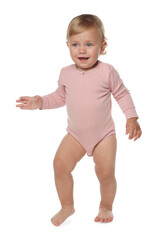 Cute baby girl in pink bodysuit learning to walk on white background