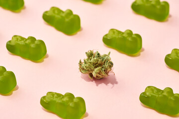 Green dry marijuana bud and candies on beige