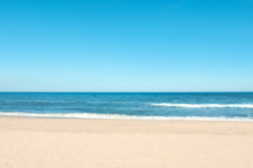 Fototapeta na wymiar Blurred view of beautiful sea and sandy beach on sunny day