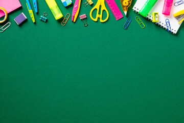 Back to school background. Flat lay colorful school supplies on green table. Top view, copy space.