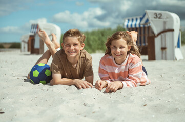 Happy children lying on white sand at sea at sunny day