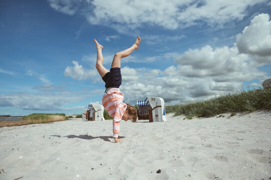 Happy teen girl joyful jumping on white beach at Baltic sea at summer holidays