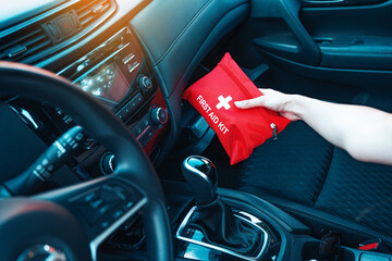 Female hand taking red first aid kit from the car glove box. A well-equipped car for road trips...