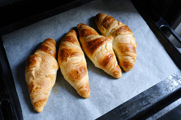 Ready crispy croissant on parchment paper. Fresh homemade cakes. Delicious traditional french crispy croissants for breakfast
