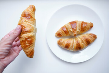 Ready crispy croissant on a white plate. Fresh homemade cakes. Delicious traditional french crispy croissants for breakfast
