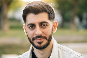 Face of caucasian ukrainian man looking at camera. Portrait young pretty brunette guy outside at...