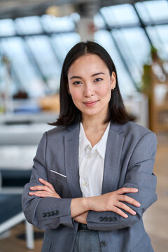 Young confident Asian business woman entrepreneur, elegant professional company manager, successful businesswoman executive leader wearing suit standing in office with arms crossed. Vertical portrait