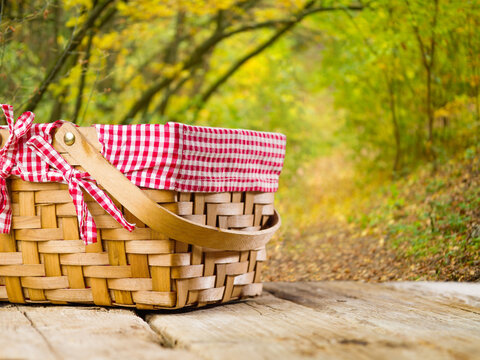 Autumn outdoor recreation. Picnic basket on a wooden table against the backdrop of beautiful autumn nature. Clear sunny day. Delicious healthy food, family fun.