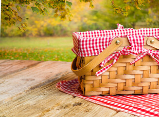 Family outdoor recreation, picnic. Cozy straw picnic basket on a wooden table against the backdrop...