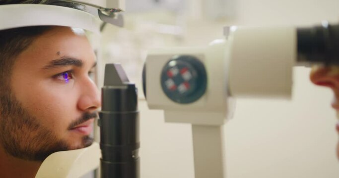 Optometrist doing an eye test on a patient in a clinic. Optician assessing the vision of a young man with a tonometer machine. Eye care professional helping to correct sight with prescription lenses