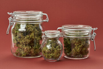 Three glass jars with dry crushed marijuana buds