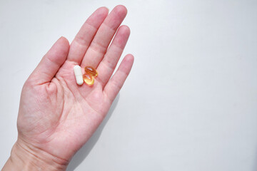 Pill close-up on a white background in a hand. Taking vitamins or medications. The concept of healthcare, medicine, pharmacies, disease prevention