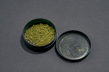 Opened plastic jar with dry cutting marijuana buds