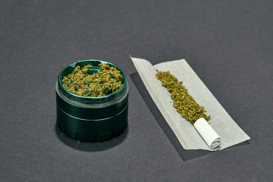 Dry crushed marijuana in jar and on paper on grey